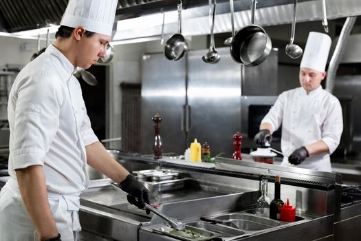 Modern kitchen. Chefs prepare dishes on the stove in the kitchen of a restaurant or hotel.