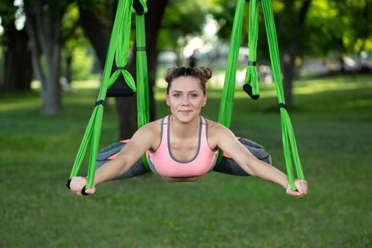 Anti-gravity Yoga, woman doing yoga exercises in the park