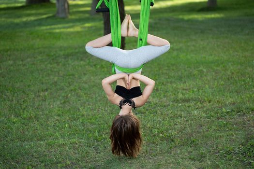 Little girl doing yoga exercises with a hammock in the park