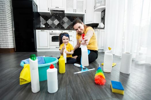 Mom and daughter are ready to clean the apartment, spraying detergent from the spray gun.