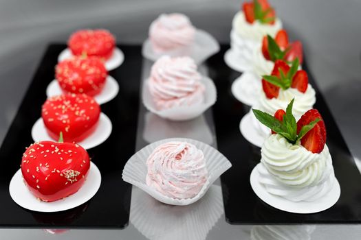 Pavlova meringue, marshmallows and mousse cake on the table in the pastry shop.