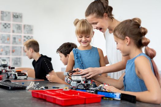 Education, children, technology, science and people concept - group of happy kids with laptop computer building robots at robotics school lesson