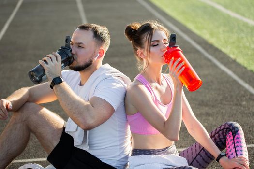 Young athletes after training sit and drink water at the stadium