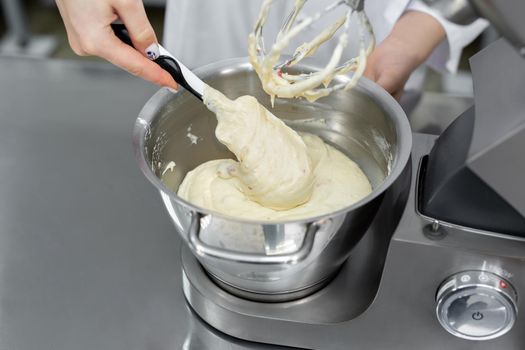 Pastry chef adds flour to the bowl of the mixer.