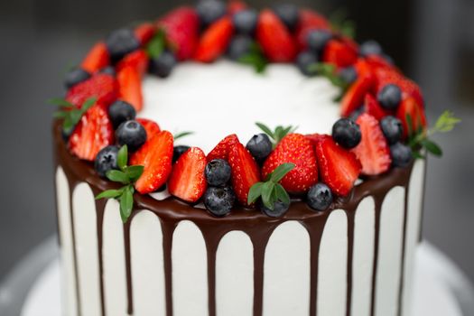 Cake with chocolate streaks and berries in the kitchen