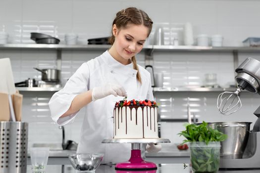 Pastry chef decorates the cake with chocolate levels of berries and mint.