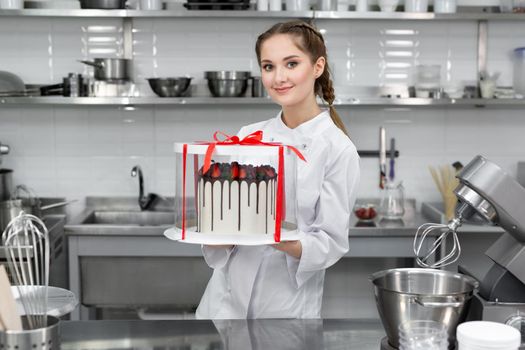 Pastry chef is holding a cake in a package.