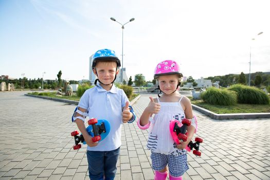 Portrait of small children of a boy and a girl in a park with skates