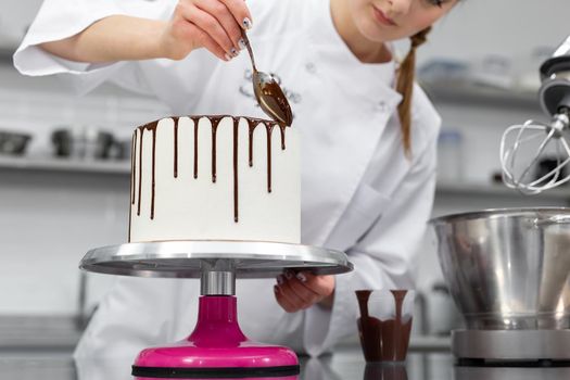 Pastry chef decorates the cake with chocolate streaks.