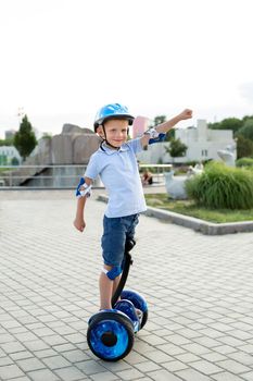 Happy little boy riding on hoverboard or scooter in the Park