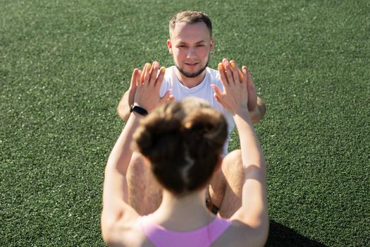 Man and a woman pump their abs in the park on the grass