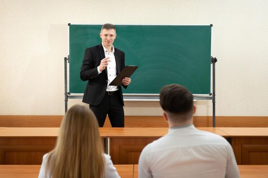 Teacher giving a lecture in a classroom and writing math formulas on the board