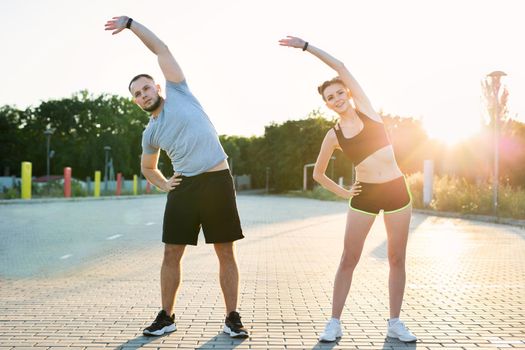 Young couple trains outdoors in a Park in the summer at sunset