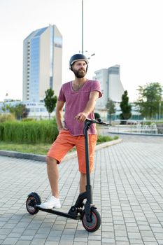 Happy man rides an electric scooter in the park