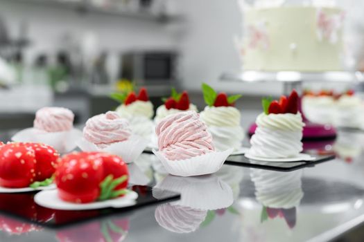 Pavlova meringue, marshmallows and mousse cake on the table in the pastry shop.