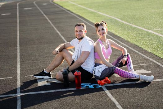 Man and a woman sit in the stadium and laugh. Outdoor sports activities