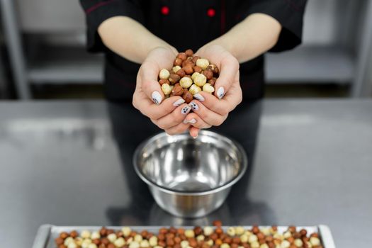 Pastry chef holds a lot of hazelnuts in his hands.