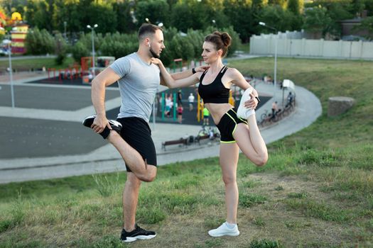 Young couple trains outdoors in a Park in the summer at sunset
