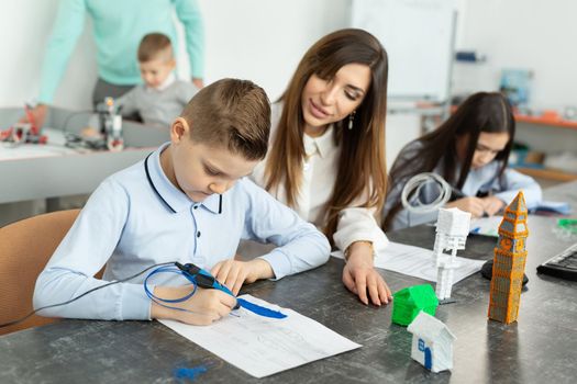 Lesson in the robotics hall. Mom and son use a pen for 3D printing.