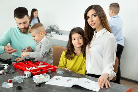 Family with children in a robotics club makes a robot controlled from a constructor.