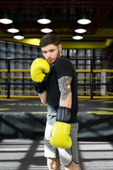 Collected sportsman in the boxing hall practicing boxing punches during training