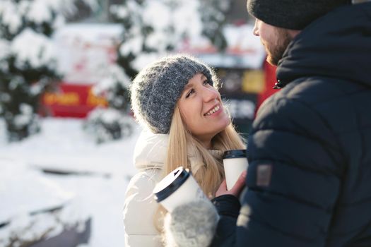 Close-up portrait of a happy couple: men and women hugging and laughing in a winter snow park.