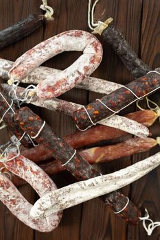 A variety of sausage products in close-up on a brown wooden background.