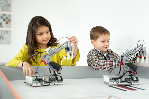 Boy and girl playing with a handmade robot. DIY robotics projects, fun and development, after school leisure.