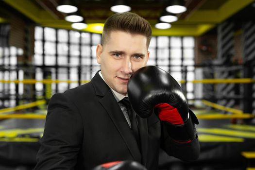 Portrait of a young male businessman in boxing gloves, who looks at the camera.