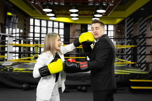 Office couple in boxing gloves wrestle in the ring.