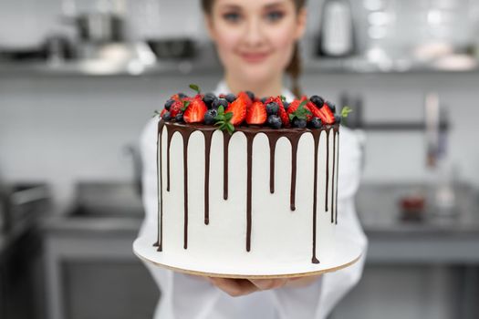 Close-up of a cake in the hands of a pastry chef.