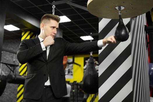 An evil businessman hits a punching bag in the gym. The concept of anger management.