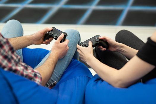 Close-up of the hands of a man and a woman enjoying playing video games with a console gamepad in their hands.