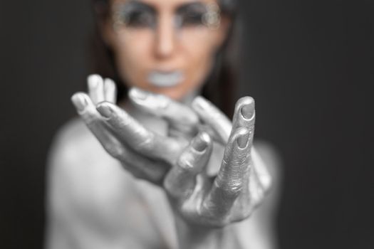 Close-up of a beautiful woman's hands with silver paint on her skin and hair.