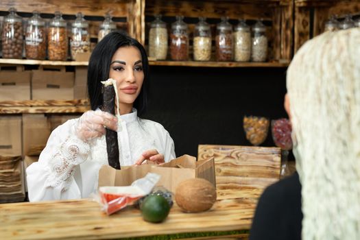 Saleswoman packs a shopping bag with goods in a health food store.