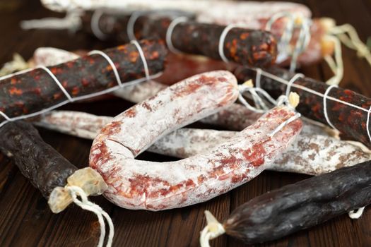 A variety of sausage products in close-up on a brown wooden background.
