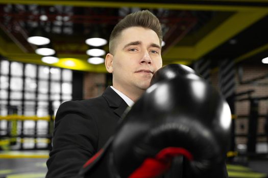 Portrait of a young male businessman in boxing gloves, who looks at the camera.