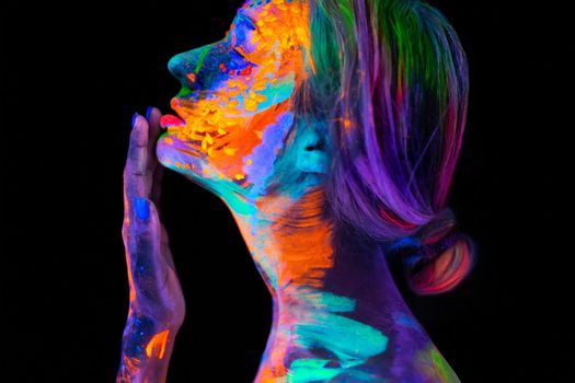 Beautiful young woman in neon light. Portrait of a model with fluorescent makeup posing in UV light with colorful makeup