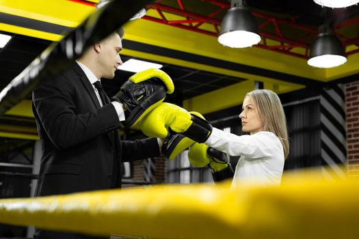 Boss trains his employee in boxing gloves in the ring