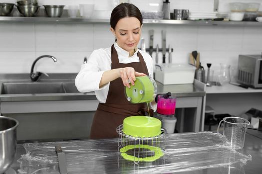 Female pastry chef decorates a mousse cake with a mirror glaze.