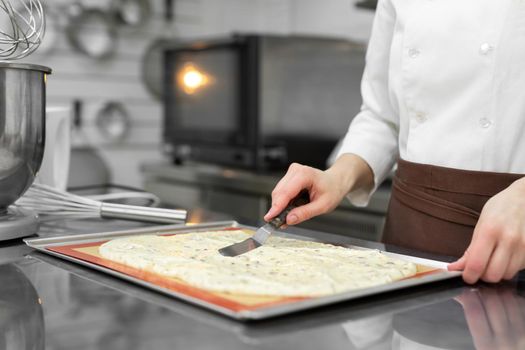 Pastry chef levels the sponge dough on parchment before baking.