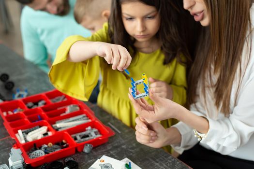 Close-up of a mother and daughter's hands at school making a robot controlled from a construction kit.
