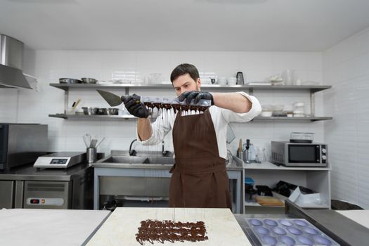 Chef or chocolatier makes sweet chocolates in a professional kitchen