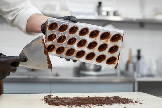 Chef or chocolatier makes sweet chocolates in a professional kitchen