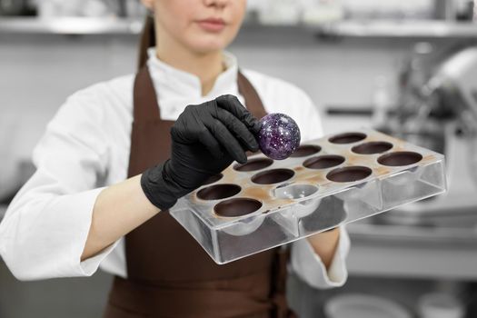 Close-up, a female pastry chef takes out a handmade chocolate candy from a polycarbonate mold