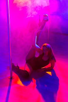 Attractive young sexy female pole dancer performs
