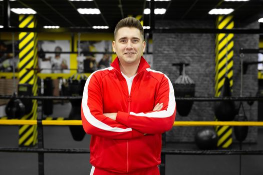 Man in a red tracksuit poses and has fun in the boxing ring