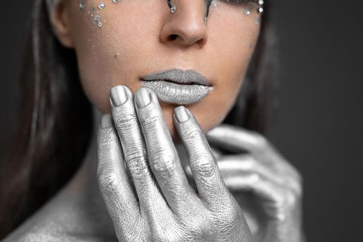 Portrait of a beautiful woman with silver paint on her skin and hair.