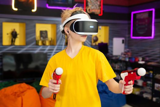 Teen, baby boy playing on a video game console, emotional gamer shooting a game using a gun controller in a game club. VR