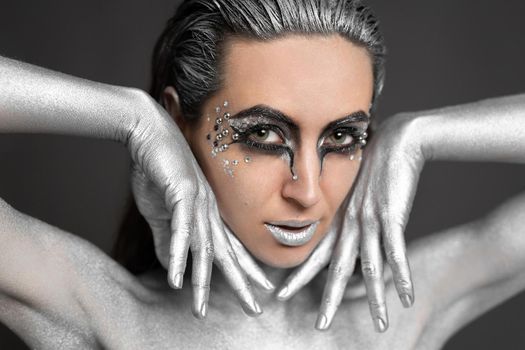 Portrait of a beautiful woman with silver paint on her skin and hair.